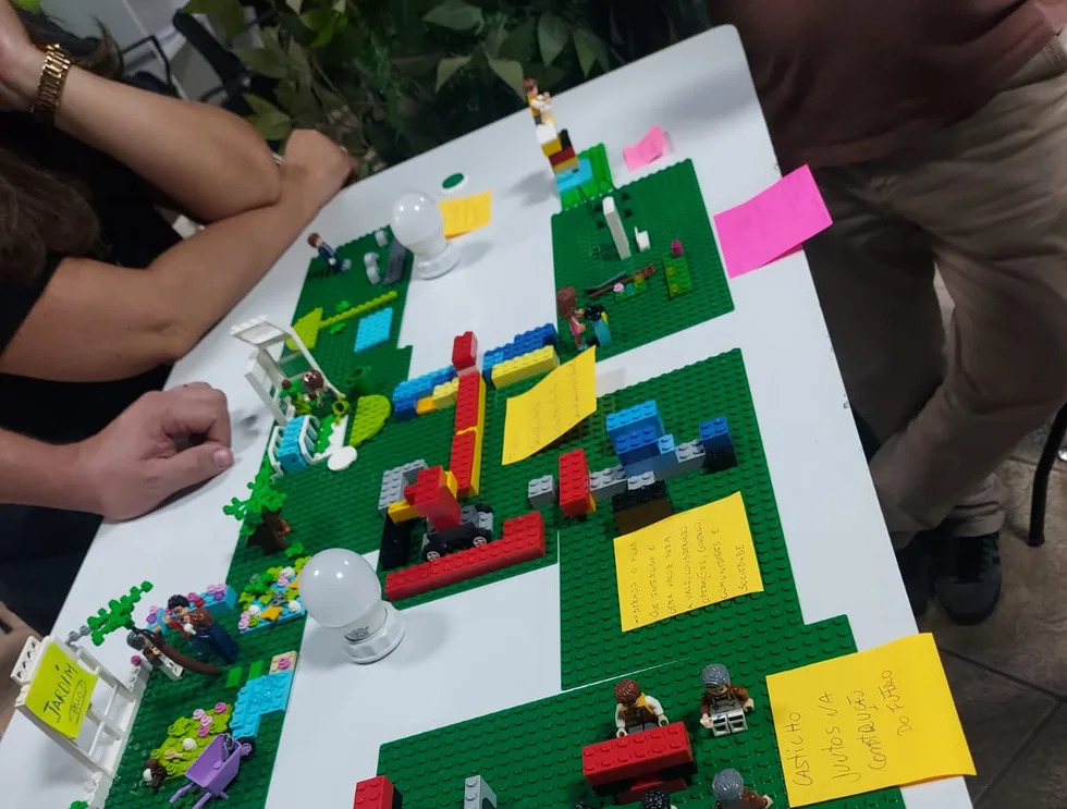 Mesa de LEGO Serious Play com as construções de uma equipe e post-its com as ideias