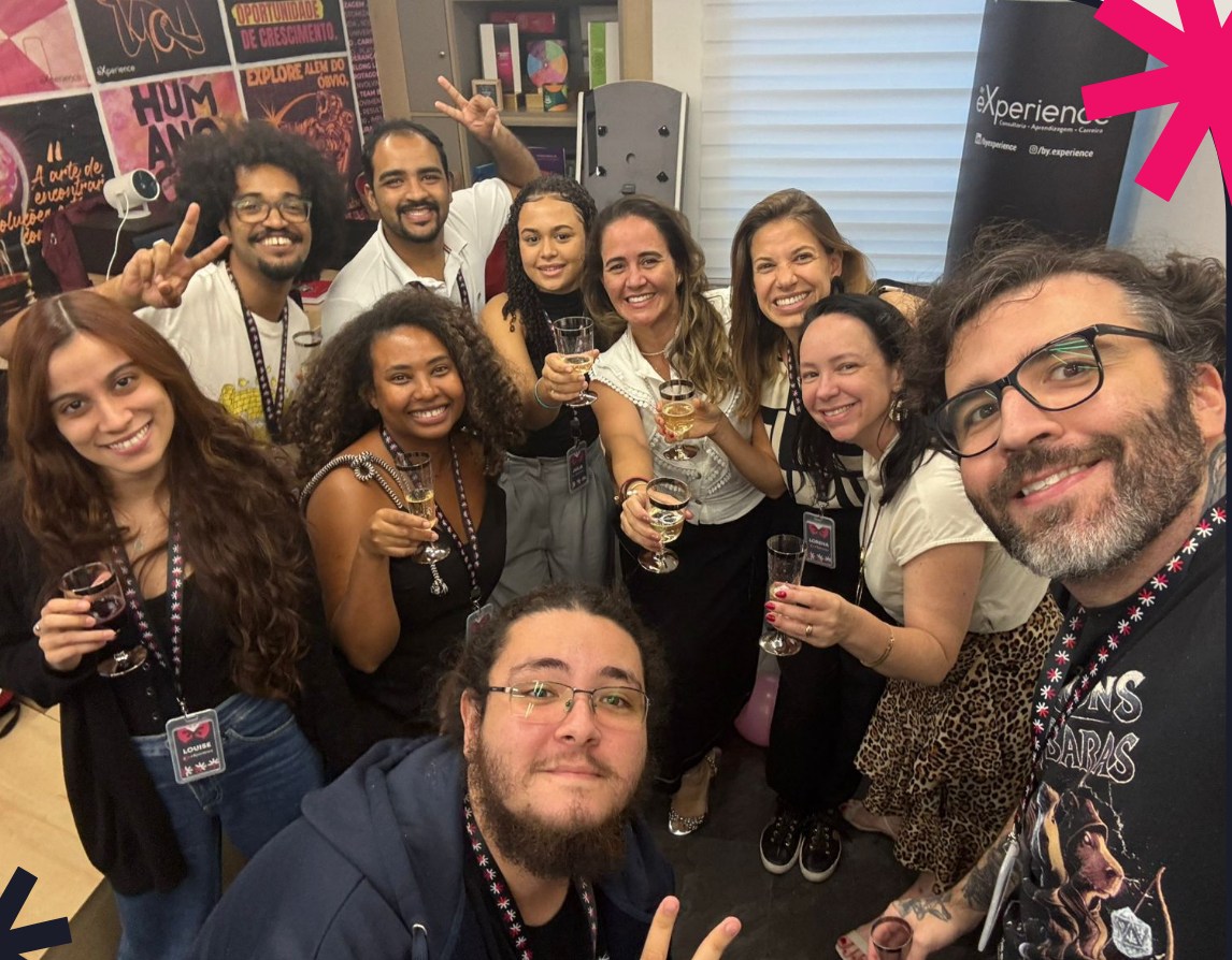 Equipe da By eXperience reunida num encontro, brindando e sorrindo para a câmera